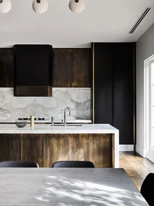 Modern kitchen featuring marble countertops, wooden cabinets, and metal accents.