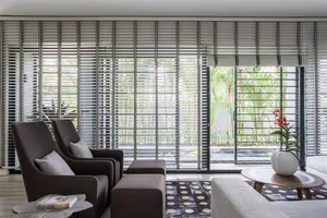 Modern living room featuring dark wood furniture and large windows with shutters.