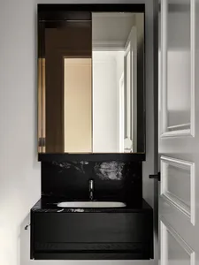 Modern bathroom with black marble sink and vanity, framed by a large rectangular mirror with a black wooden frame.