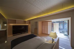 A modern, minimalist bedroom featuring wood furniture and a TV cabinet with backlighting.