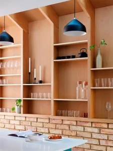 A modern minimalist kitchen with wooden shelves, white countertop, and black pendant lights.