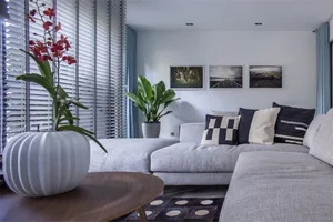 Modern minimalist living room with grey L-shaped sectional sofa, patterned cushions, wooden coffee table, floor-to-ceiling wi