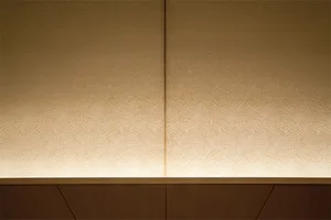 A textured paper wallpaper with illuminated lighting on a wooden wall.