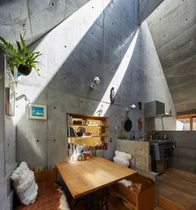 A cozy industrial kitchen with wooden table and concrete walls