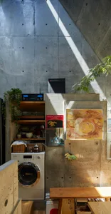 A modern kitchen with concrete walls, wooden countertops, and metallic appliances.