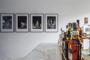 A modern bar area featuring a marble countertop with a selection of liquor bottles and framed artwork on the wall.