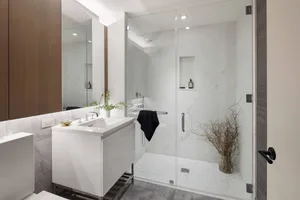 A modern bathroom featuring marble and glass walls, concrete floor, and a glass shower enclosure.