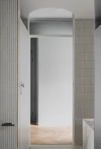 A modern interior space featuring a glass door leading to a corridor with wooden flooring and concrete walls.