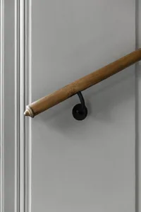 A wooden handrail mounted on a gray wall, providing support in an interior setting.