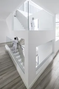 Minimalist, glass staircase interior with white walls and wooden flooring.