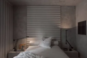 Modern minimalist bedroom featuring a fabric headboard and soft lighting.