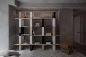A modern living room with a wooden shelf and concrete walls.