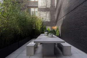 Modern, minimalist outdoor sitting area designed with concrete elements and surrounded by greenery.