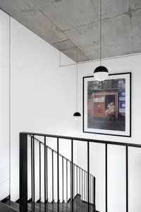 A minimalist industrial staircase with concrete walls and black metal railings, featuring a framed photograph of people in a 