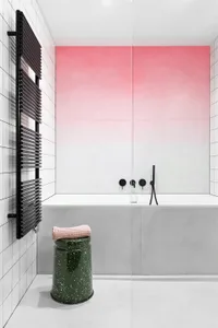 A modern, minimalist bathroom featuring a white concrete bathtub, white tiles, and a pink ombre wall above the tub.