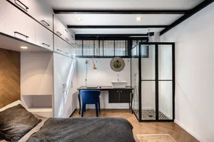 Modern minimalist bedroom with black, white, and gray color scheme, featuring a wooden bed, white floating cabinets, and a sm