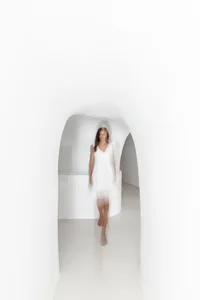 Blurred female figure in a minimalist, all-white environment