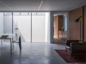A minimalist living room with a concrete floor and a wooden armchair.