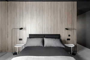 Modern bedroom featuring a wood-paneled wall, black bed frame, and gray duvet and pillows.