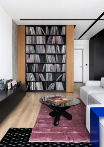 Modern living room featuring a tall bookshelf filled with books, a round black coffee table with books on it, and a white sof