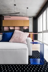 Modern living room featuring a grey sofa adorned with blue and pink pillows, and a blue metallic side table on a black and wh