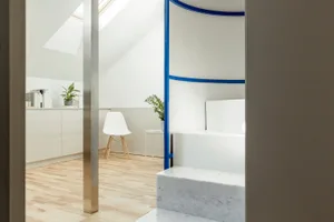 A modern living room with white walls, a white chair, a blue and white geometric structure, and a marble floor.