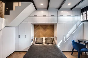 A modern minimalist bedroom with a bed, cabinets, and a window.