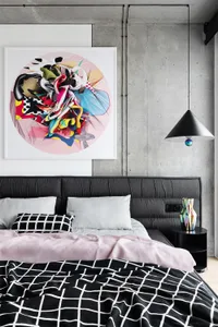 A modern minimalist bedroom with a grey bed, pink accents, and abstract art hanging above the headboard.