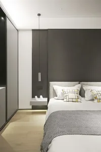 A modern minimalist bedroom featuring a textured dark grey wall, a white bed with grey and white patterned pillows, a wooden