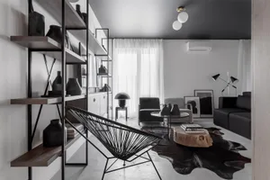 Modern minimalist living room with black, white, and wood furniture, concrete floor, and metal shelving.