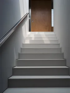 Modern white staircase with wooden door at the top.