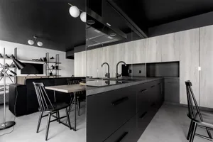 A modern, minimalist kitchen with sleek black cabinets and light wooden counters, featuring a clean, contemporary design.