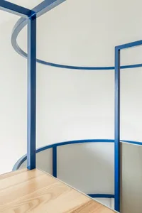 Modern interior design featuring a blue railing with curved sections and wooden flooring.