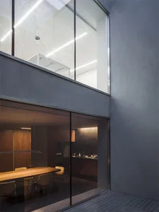 A modern kitchen interior with a glass wall and wooden dining table.