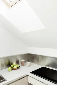 Modern kitchen counter with metallic backsplash and skylight above.