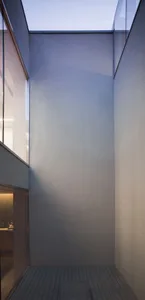 A minimalist, modern interior space with concrete walls and a high ceiling.