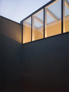 A modern interior space featuring large glass walls, creating a bright and open atmosphere.