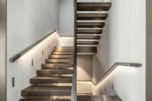 Modern metal staircase with illuminated steps and handrails.