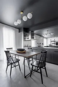 Contemporary kitchen with white cabinets, metallic surfaces, and concrete flooring.