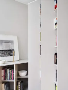 A modern home library with white shelves and a white framed artwork featuring a black and white photograph.