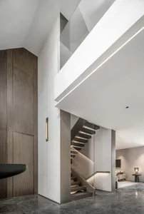 A modern interior featuring a staircase intersection with concrete flooring, minimalist lighting, and wood and glass material