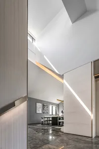 A modern living room with concrete walls and floor, featuring minimalist furniture and large windows.