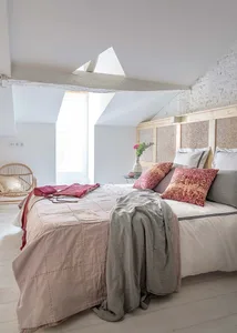 A minimalist bedroom with a textured wood headboard, pink and beige bedding, and a skylight window.