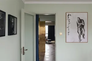 A modern entryway with mixed materials, including a glass panel door, blue curtains, and a large framed artwork of a man carr