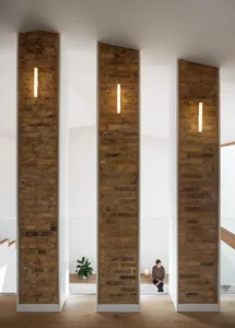 Modern living room featuring brick columns, glass ceilings, and wooden floors.