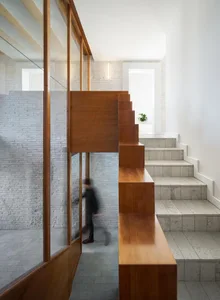 A modern minimalist staircase made of wood, concrete, and brick materials.