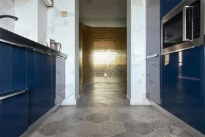 Modern residential kitchen interior featuring white marble countertops and hexagonal tiled floor