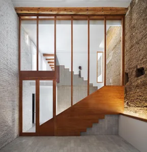 Modern staircase featuring glass panels and brick walls