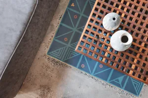 A wooden table with a geometric patterned tile background featuring concrete tiles and decorative vases.