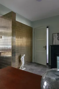 Metal tile wall in an entrance hall, featuring a wooden table and a statue.